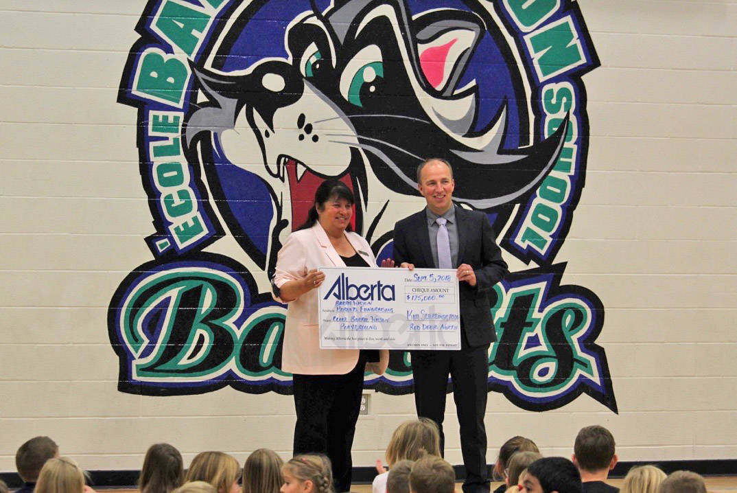 Kim Schreiner presents a cheque of $125,000 to Chris Good of Barrie Wilson Elementary School, which will go towards their new playground. Carlie Connolly/Red Deer Express